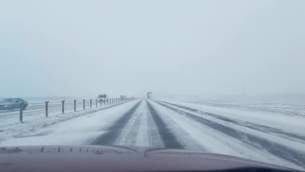 Gevaarlijk rijden op een gladde en besneeuwde snelweg in een sneeuwstorm in de winter. IJs op de weg, autoverkeer, slecht weer — Stockvideo