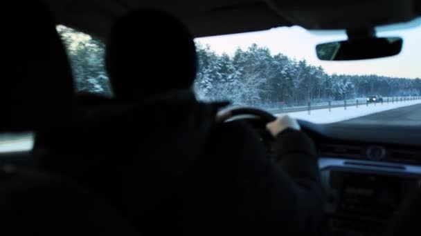 Een mannelijke bestuurder rijdt een auto op een 's avonds winterweg bij koud weer. Winter auto rijden concept, lange afstand reis, close-up — Stockvideo