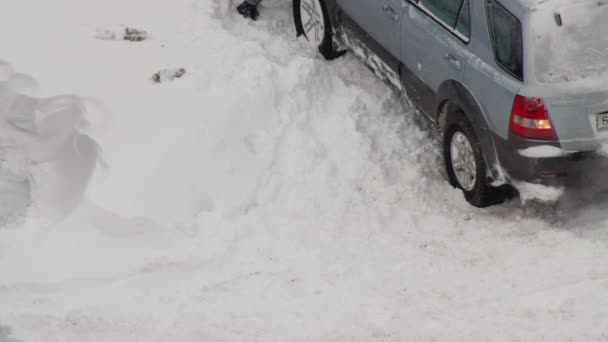 Un coche de pasajeros se desliza en la nieve en los neumáticos de invierno en el patio de la casa. Superficie resbaladiza bajo la nieve, el hielo, la rueda — Vídeos de Stock