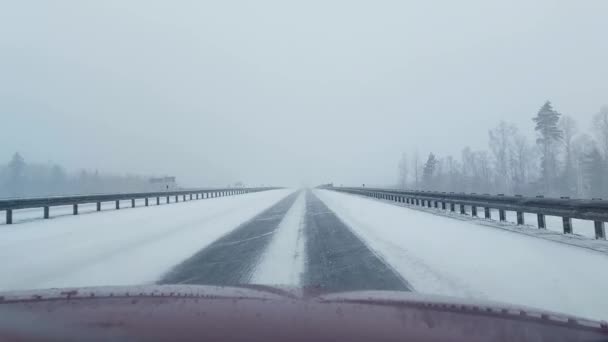 Autorijden op een landweg in de sneeuw. IJs op straat in de winter. Gevaar op de weg, slecht weer — Stockvideo