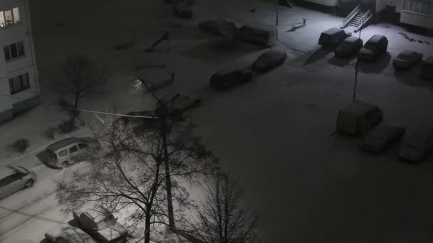 Schneesturm mit Wind auf der Straße im Innenhof der Stadt in der Nacht. Schneeflocken auf dem Hintergrund eines Laternenmastes. Kopierraum für Text — Stockvideo