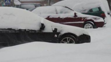 Kış. Park halindeki arabalar karla kaplıydı. Güçlü bir rüzgar esiyor. Ağır çekimde kar yağışı. Trafik ve kar fırtınası için kötü hava koşulları. Trafik kazası tehlikesi. Kesişen yol