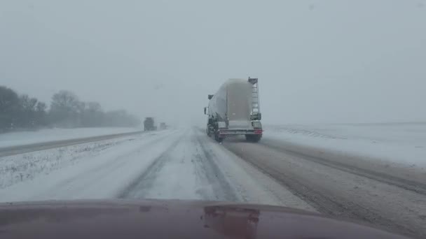 Обгон грузовика полуприцепом на снежном шоссе в плохую погоду зимой. Скользкая дорога из льда, колли на дороге — стоковое видео