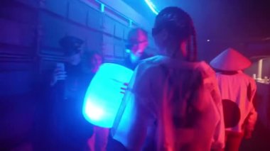 Siberpunk gelecek konsepti. Dişi cyborg neon ışıklarıyla şehirde dolaşıyor. Bilim kurgu sahnesi, fantezi, bilim. Sette. Kız panikle etrafına bakıyor ve kovalamacadan kaçıyor. Yarının Dünyası