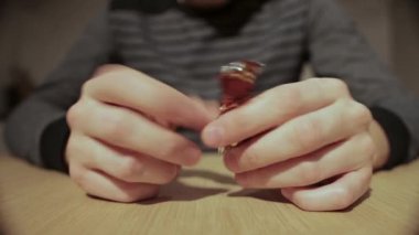 Bir adam elindeki şeker ambalajını çevirir ve fırlatır, yakın plan.