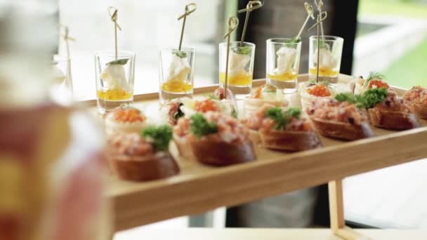 Un aperitivo hermoso, sándwiches de pescado rojo con caviar en la mesa festiva. Hermoso ajuste de mesa, primer plano — Vídeos de Stock