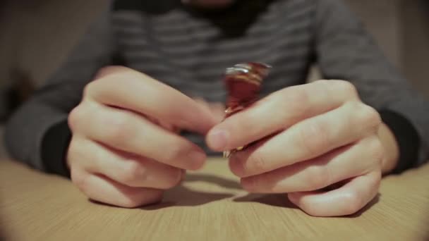 Een man verdraait een snoeppapiertje in zijn handen en gooit het weg, close-up — Stockvideo