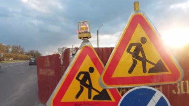 Güneşli bir günbatımının arka planında yol tamiri ile ilgili üçgen tabelalar. Metin için alanı kopyala