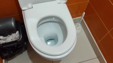 Turuncu duvarları ve beyaz tuvaleti olan temiz modern tuvalet, yakın plan.