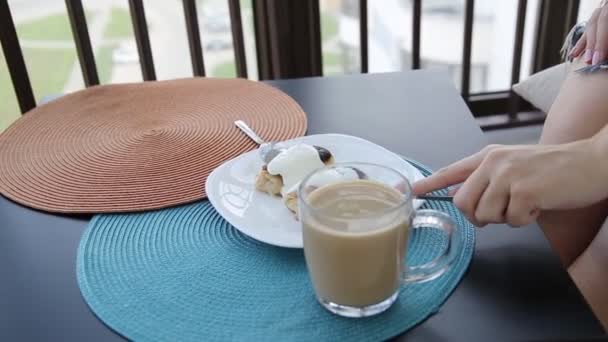 Κορίτσι σπάει ένα κομμάτι τηγανίτα με ξινή πιρούνι κρέμα το πρωί πρωινό στο μπαλκόνι, close-up — Αρχείο Βίντεο