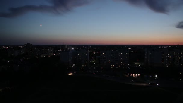 Timelapse de lumini de oraș de noapte pe fundalul cerului cu luna. Lumini în ferestrele caselor și mașini care trec cu faruri. Copiați spațiul pentru text — Videoclip de stoc