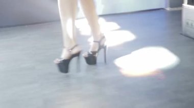 Gece kulübünde yüksek topuklu ayakkabı giyen bir dansçının bacakları. Hafif müzik, yakın çekim.