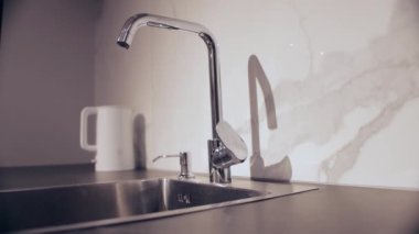 Mutfak musluğundan su damlıyor, suyu idareli kullanıyor. Metin için alanı kopyala