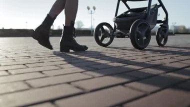 Genç ve güzel bir kız, sonbaharda güneşli bir günde sokakta bir bebek arabasıyla yürüyor. Yeni doğmuş bir bebekle yürümek, annelik.