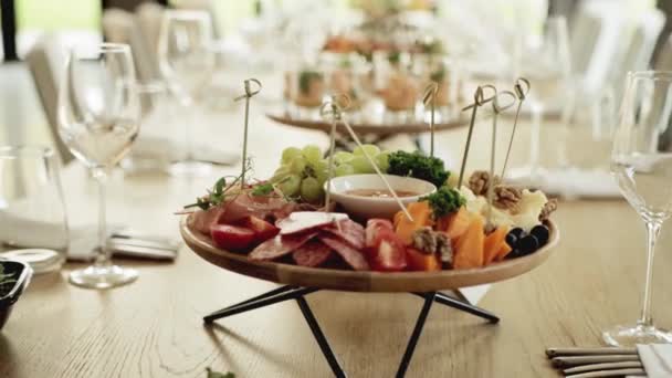 A festive platter of sausage and cheese appetizers stands on the festive table, close-up — Stock Video