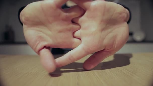 En man sitter vid ett bord och knådar sina fingrar och sträcker sig, närbild — Stockvideo