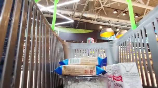 BOBRUISK, BELARUS - 02,09,2021 : Un homme achète des produits d'épicerie dans un supermarché et les met dans un panier. Vue depuis le panier — Video