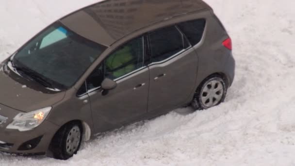 De auto glijdt uit in de sneeuw waaronder in de winter ijs op de weg ligt. Ernstige sneeuwstorm, sneeuwdrift — Stockvideo