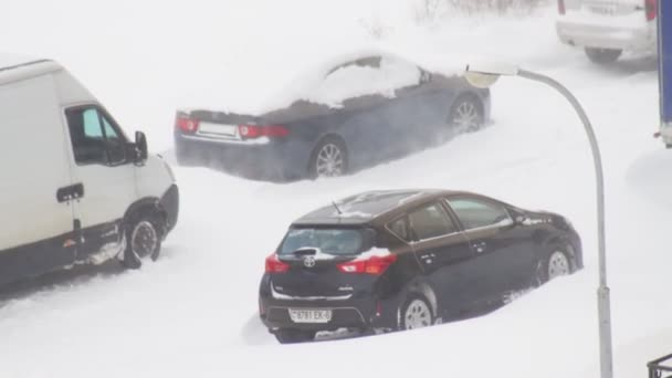 BOBRUISK, BELARUS 13.02.21: Wiatr wstrząsa latarnią, śnieżyca wiruje w powietrzu na tle samochodów na podwórku. — Wideo stockowe