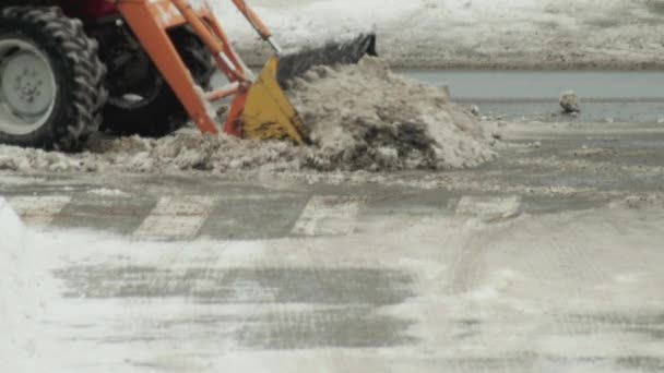 Ein Traktor reinigt mit einem Eimer Schnee auf der Straße von Schnee in der Stadt. Aufräumarbeiten in der Stadt nach Schneesturm, Industrie — Stockvideo