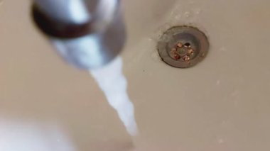 Musluktan lavaboya ve gidere su akıyor. Kanalizasyon ve su tüketimi hizmetleri için ödeme kavramı, yavaş çekim