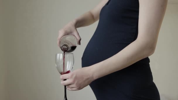 Беременная девушка наливает вино из бутылки в бокал. Беременность и алкоголизм. Риск и опасность для будущего ребенка, крупным планом — стоковое видео