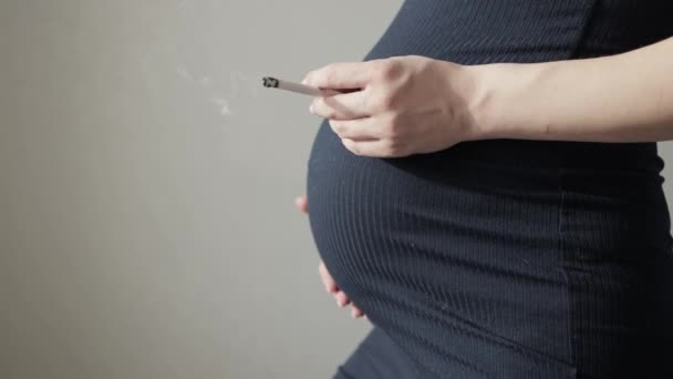 Menina fumante com um cigarro com uma barriga grande durante a gravidez. Perigos e riscos para a saúde da criança ao fumar uma mãe grávida. Espaço de cópia para texto — Vídeo de Stock