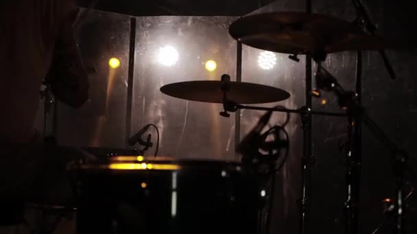 Baterista tocando un kit de batería en un concierto en un club nocturno con el telón de fondo de focos — Vídeos de Stock