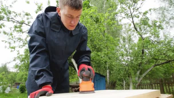 A man polishes wood with a power tool, a close-up. Handmade wood, cleaning wood with sandpaper — Stock Video