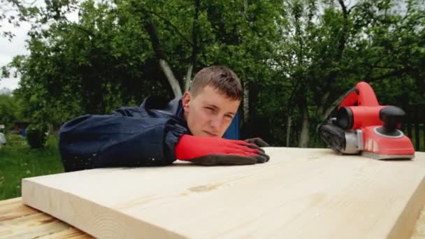 Een man verwerkt een houten oppervlak met een elektrisch vlak, close-up. Houtproducten, handgemaakt, elektrisch gereedschap — Stockvideo