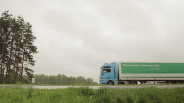 Road Bobruisk-Minsk, BELARUS - 19 mei 2021: een vrachtwagen met oplegger vervoert vracht bij nat weer met regen tegen een grijze lucht. Kopieer ruimte voor tekst — Stockvideo