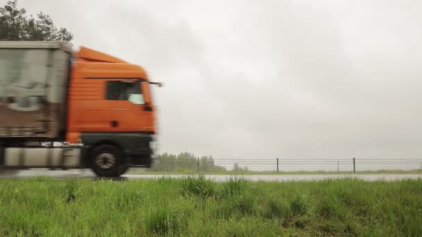 Road Bobruisk-Minsk, BELARUS - 19 mei 2021: een vrachtwagen met oplegger vervoert vracht bij nat weer met regen tegen een grijze lucht. Kopieer ruimte voor tekst — Stockvideo