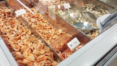 Bir dükkanın vitrininde donmuş deniz ürünleri, karides ve midye satmak.