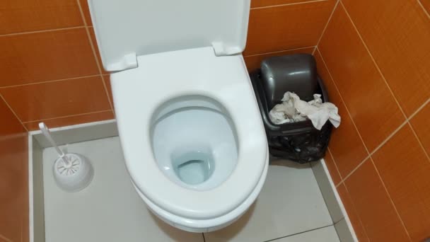 Ένας άντρας πετάει χαρτί τουαλέτας στο πάτωμα της τουαλέτας. Ακάθαρτη τουαλέτα, σκουπίδια σε δημόσια τουαλέτα, πρόβλημα — Αρχείο Βίντεο