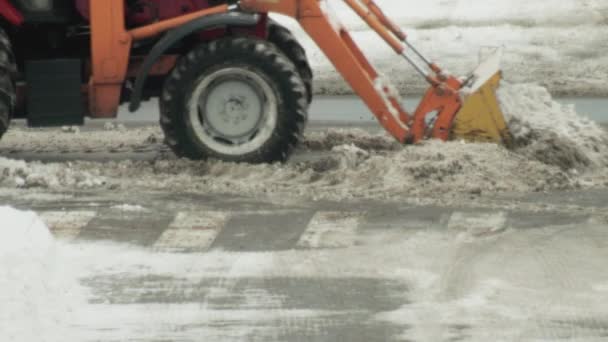Un tractor limpia la nieve con un cubo en la carretera de la nieve en la ciudad. Limpieza de la ciudad después de un ciclón de nieve, la industria — Vídeos de Stock