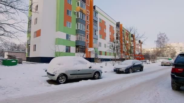 Carros cobertos de neve estão estacionados em um pátio residencial com um prédio de apartamentos no inverno. O perigo de roubo de carro. Condições meteorológicas — Vídeo de Stock