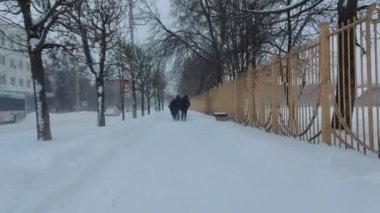 Kar fırtınası. İnsanlar kışın kar yağışı sırasında şehirde karla kaplı bir yol boyunca yürürler. Kar fırtınası. Kötü hava koşulları, soğuk iklim. Şehir sokağı. Meteoroloji