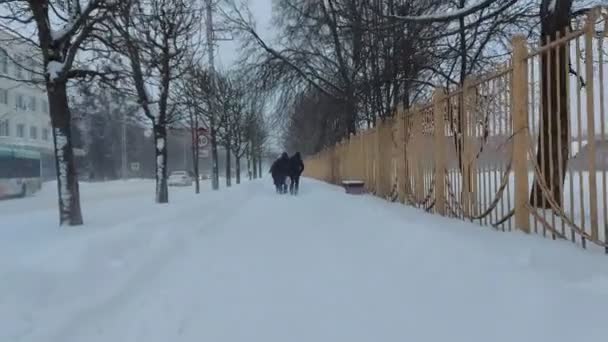 暴风雪。在冬季的降雪中，人们沿着雪地覆盖的道路走着。暴雪。恶劣的气候寒冷的气候城市街道。A.气象学 — 图库视频影像