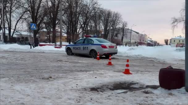 Politieauto met noodverlichting tijdens verkeersongeval of MVC in de winter als gevolg van weersomstandigheden en gladde weg. Auto met blauwe lichtbalk is op een plaats delict of overval — Stockvideo