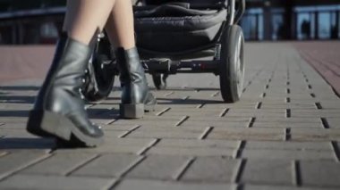 Bir kız sokakta bir çocukla birlikte parkta yürüyor. Doğa bir puset ve yeni doğmuş bir bebekle yürüyor, yakın plan.