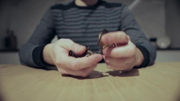 Мужчина сортирует шоколад в руках и бросает его на стол крупным планом. — стоковое видео