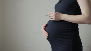 Hamilelik sırasında koca göbekli sigara içen bir kız. Hamile bir anne sigara içerken çocuk için tehlike ve sağlık riskleri. Metin için alanı kopyala