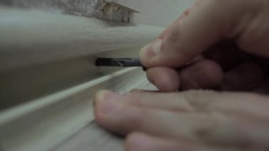 Bir işçi süpürgeliği korumak için vida takıyor. Daire tadilatı, yakın plan, zemin etek tahtası.