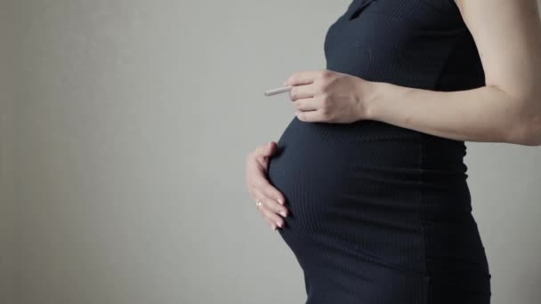 Курящая девушка с сигаретой с большим животом во время беременности. Опасности и риск для здоровья ребенка при курении беременной матери. Копирование текста — стоковое видео