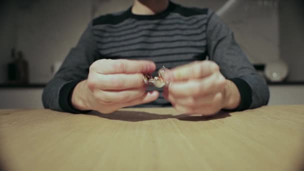 Чоловік їсть цукерки і крутить обгортку з цукерок в руках, крупним планом — стокове відео