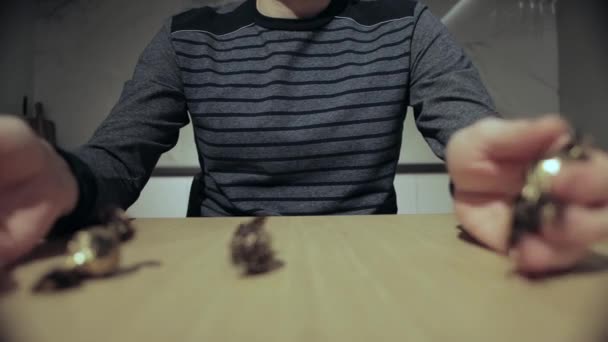 Muž se probírá čokoládou v rukou a hodí ji na stůl, zblízka. — Stock video