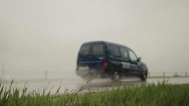 De auto rijdt op een natte weg in de regen. Gladde weg en slecht zicht op de weg, op de achtergrond. Langzame beweging — Stockvideo