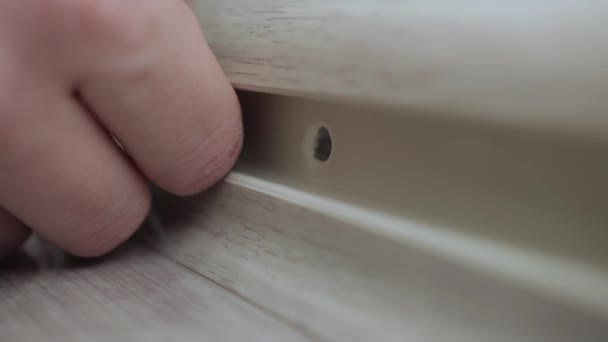 A worker installs a screw to secure the baseboard. Apartment renovation, close-up, floor skirting board — Stock Video