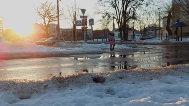 少女歩行者の女性は、信号を停止する赤い信号で道路を横断する。不遵守と交通ルール違反。冬の後の早春。氷点下。黙れ!。危険及び安全 — ストック動画