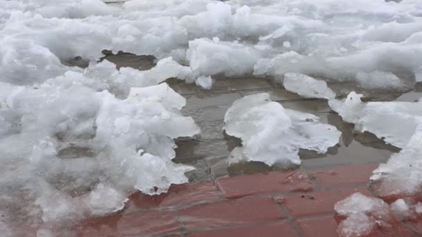 Topniejący śnieg wiosną w mieście. Strumienie wody przepływają przez miasto. Początek wiosny, tło — Wideo stockowe